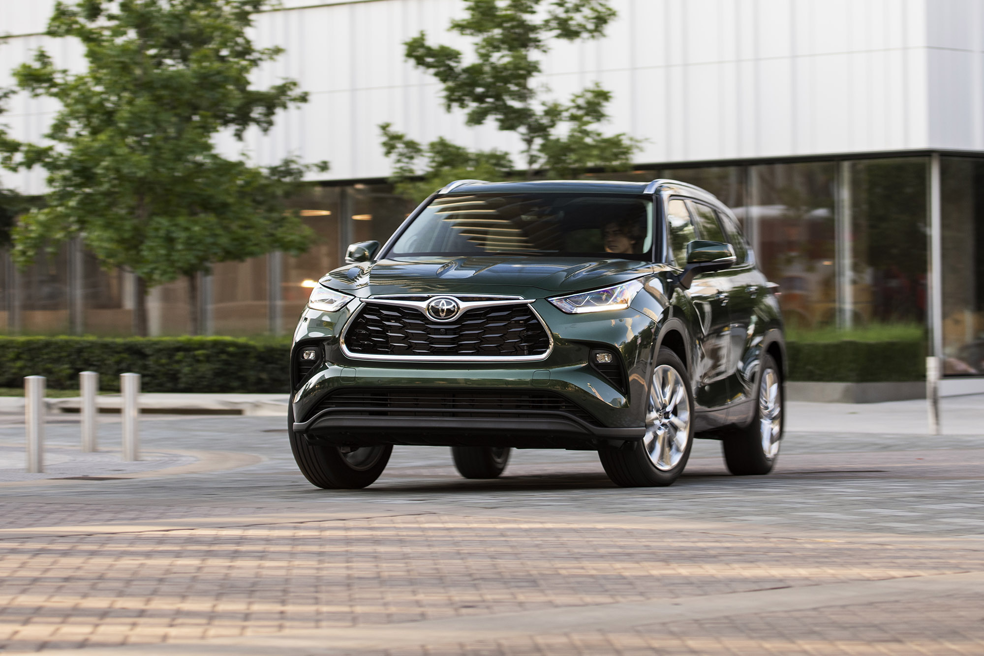 2023 Toyota Highlander in Cypress Green turning in front of a building