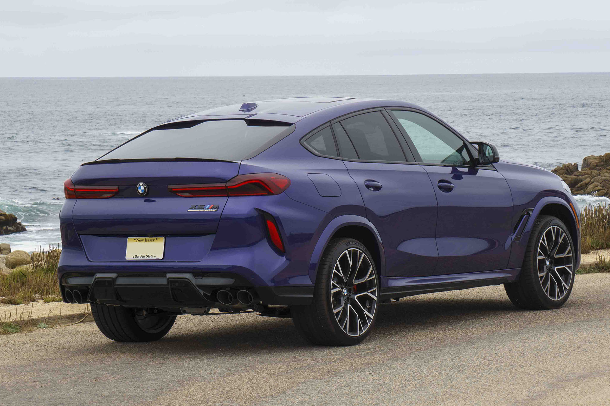 Rear right quarter view of a blue 2024 BMW X6 M