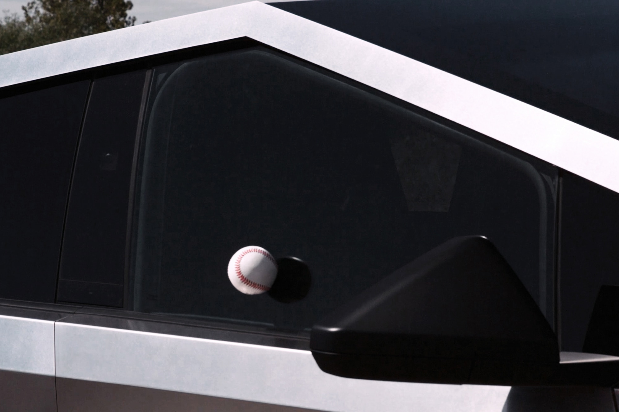 Baseball bouncing off window of a stainless-steel Tesla Cybertruck