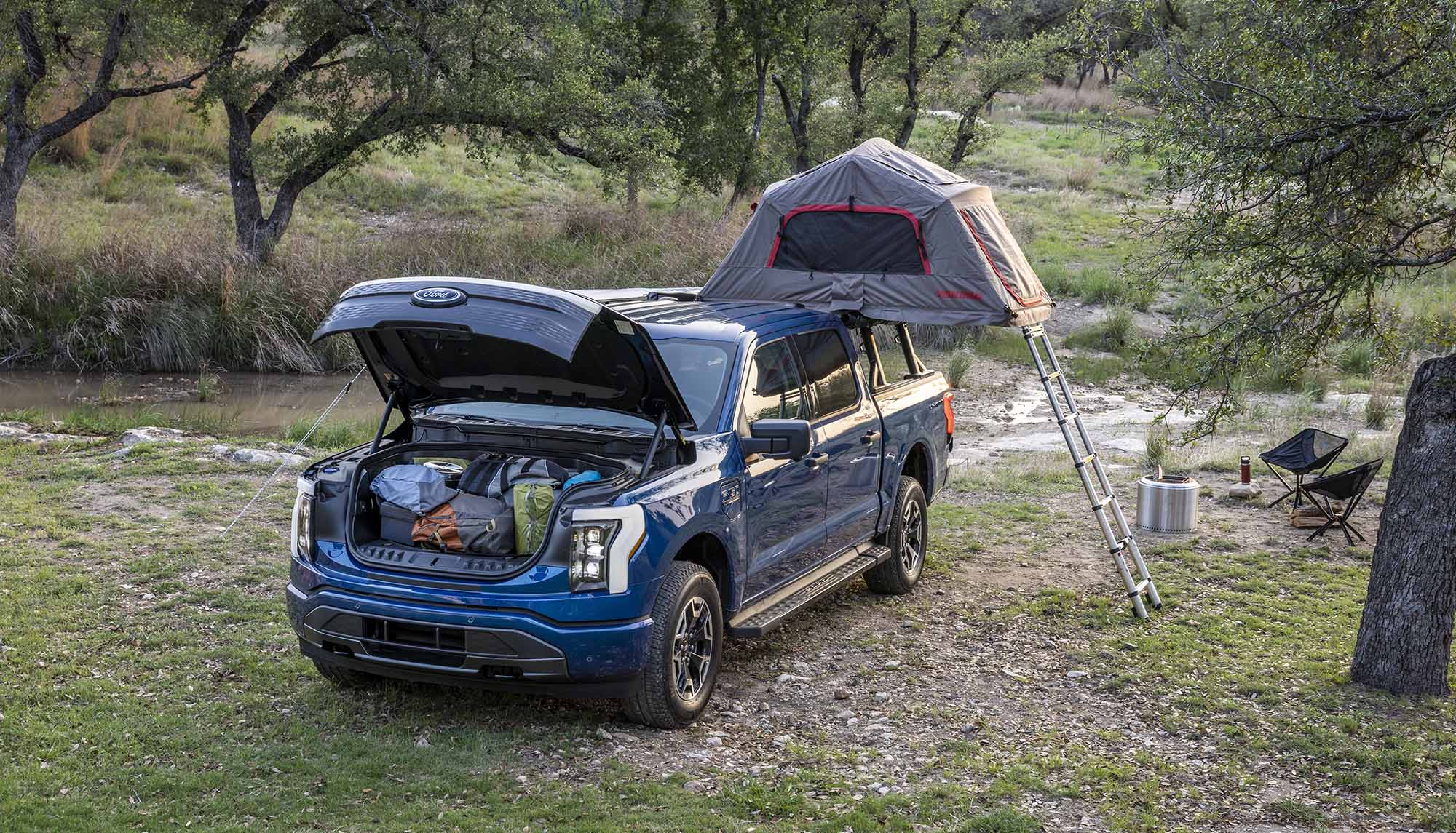 A Ford F-150 Lightning set up for camping with an above-cargo-bed tent