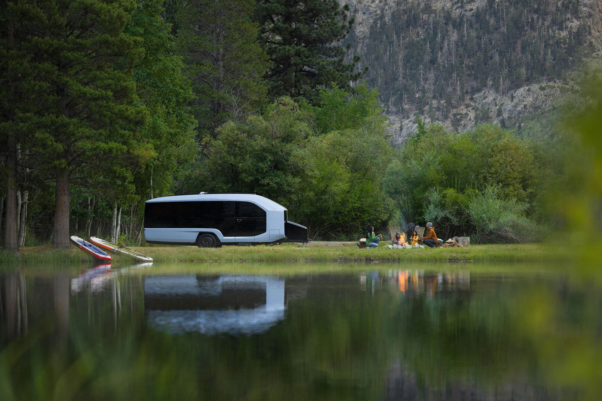 A Pebble electric camper trailer parked by a lake