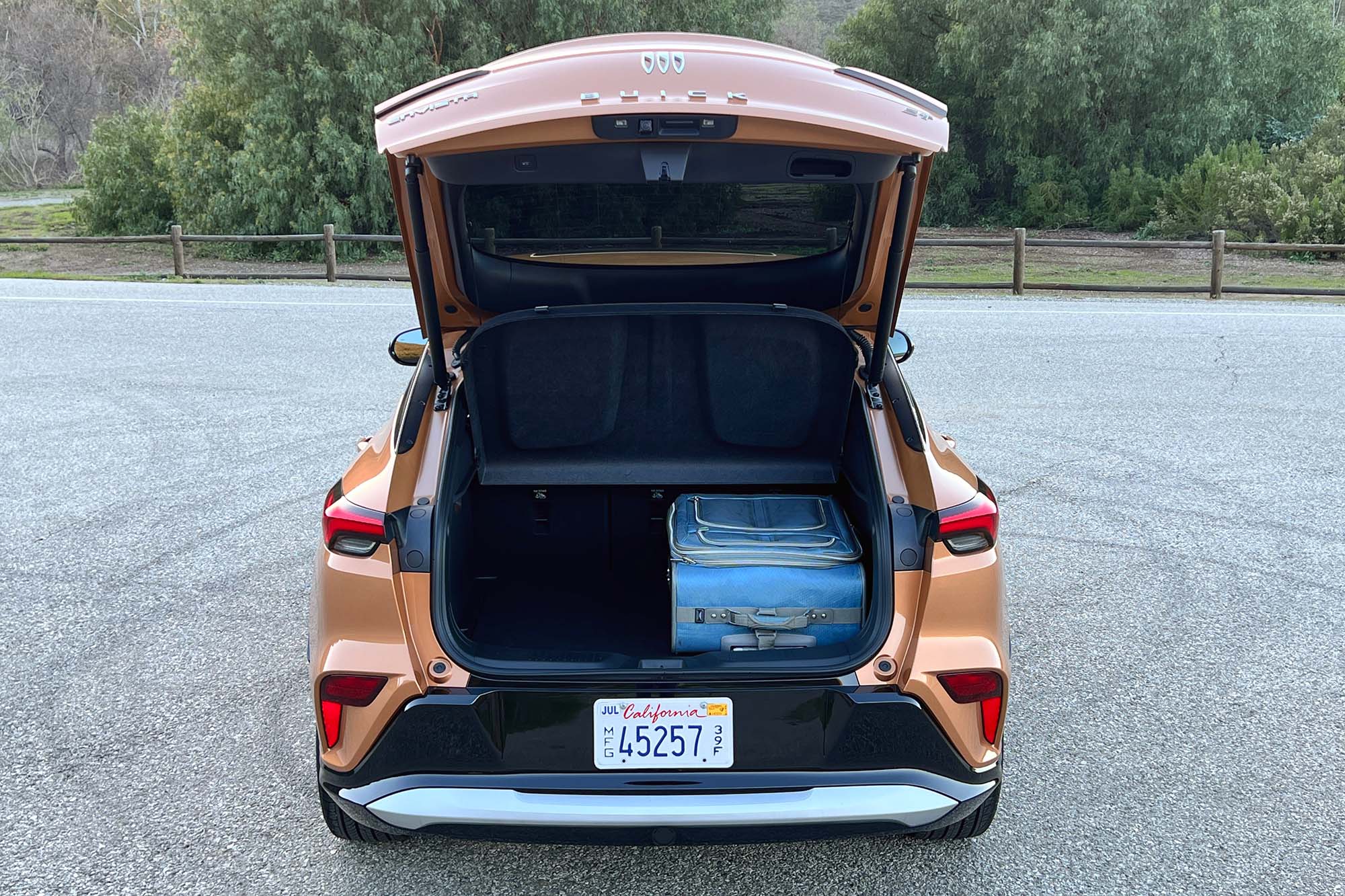 The cargo area of an orange 2024 Buick Envista holding a suitcase
