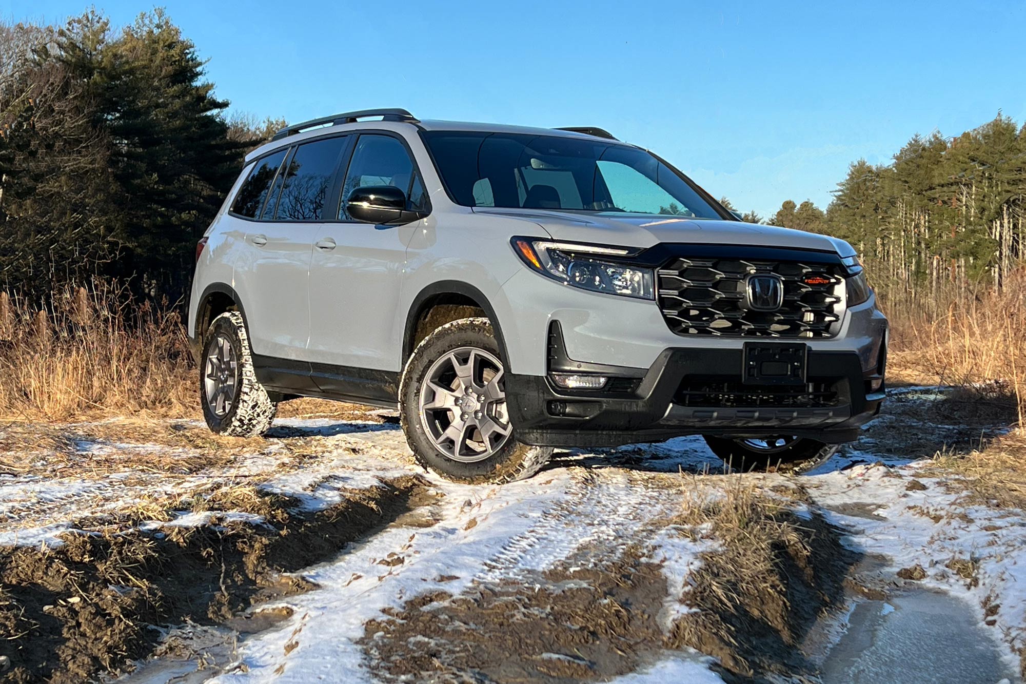 Sonic Gray 2024 Honda Passport TrailSport parked on lightly snow-covered dirt path.