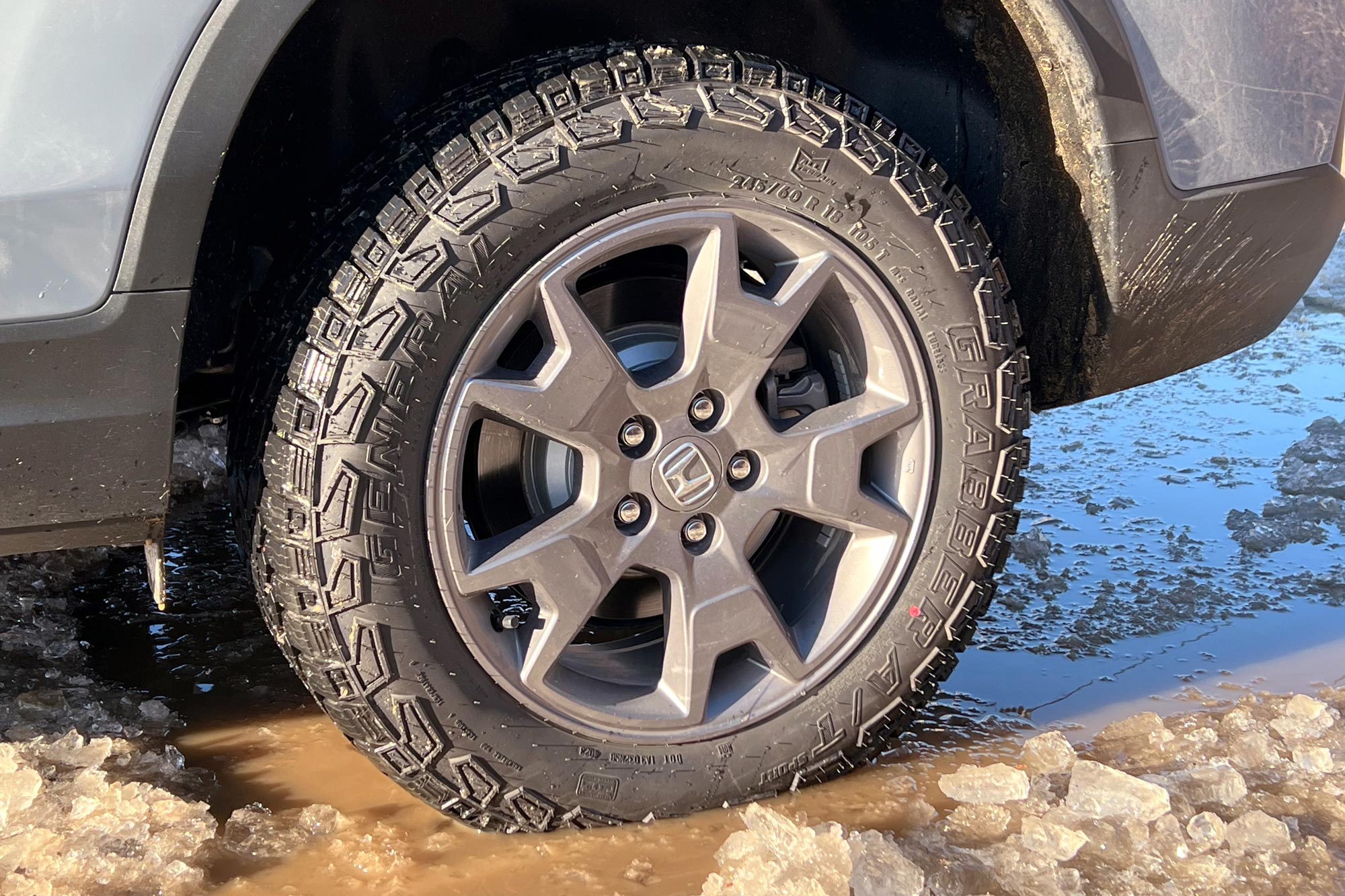 2024 Honda Passport TrailSport all-terrain tires parked in ice and slush.