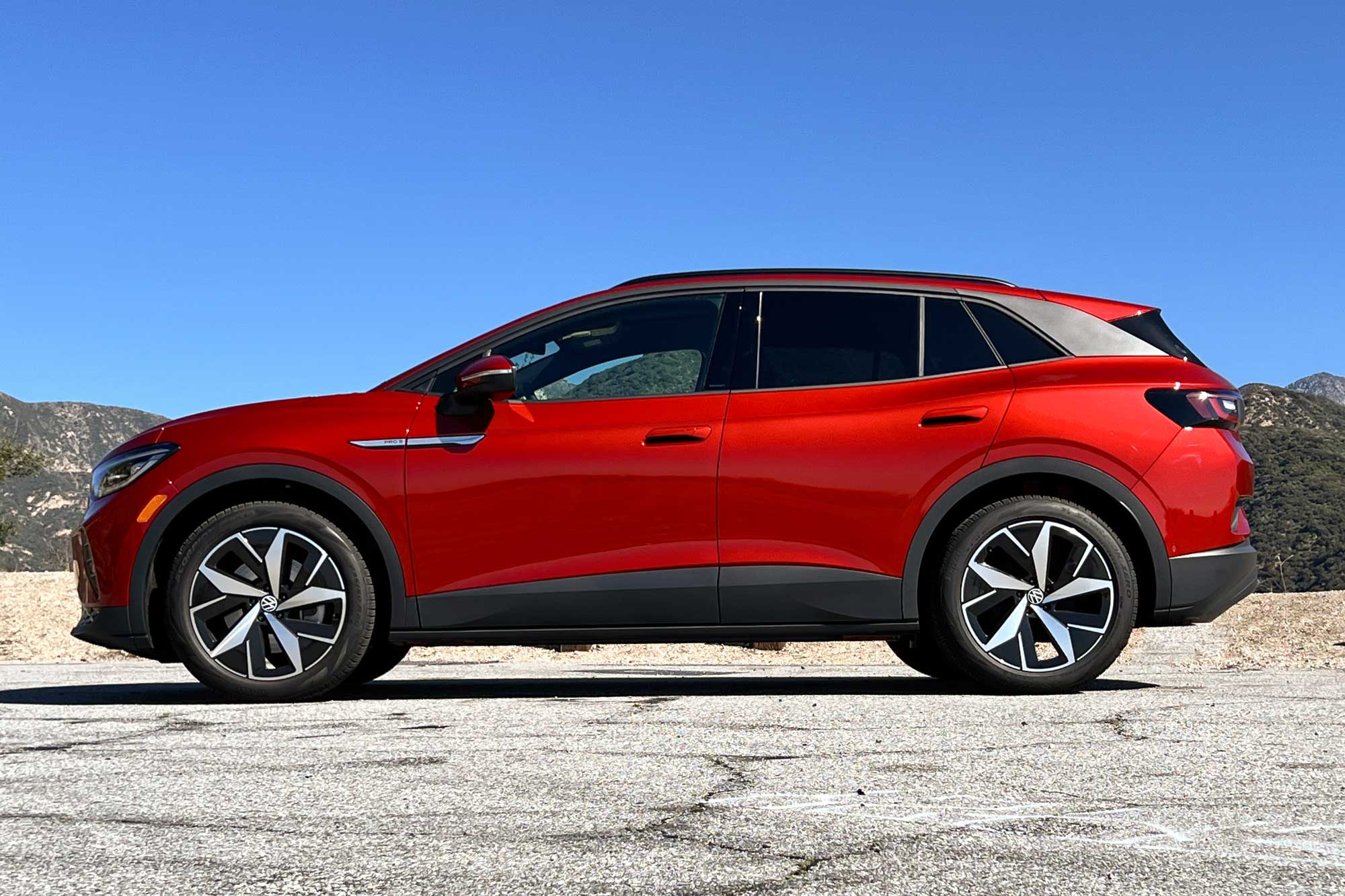 Side view of a red 2024 Volkswagen ID.4 Pro S parked on pavement near some mountains