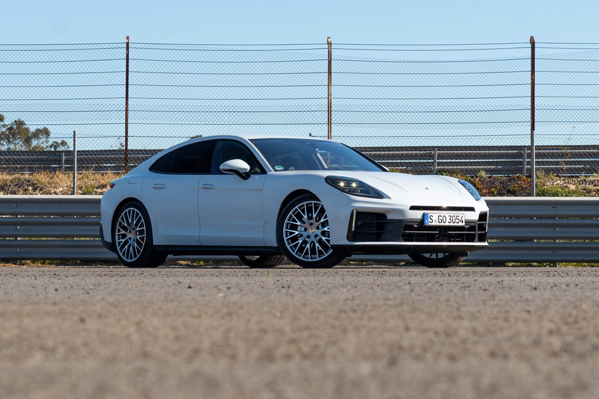 White 2024 Porsche Panamera 4 parked near guardrails and a fence on a sunny day