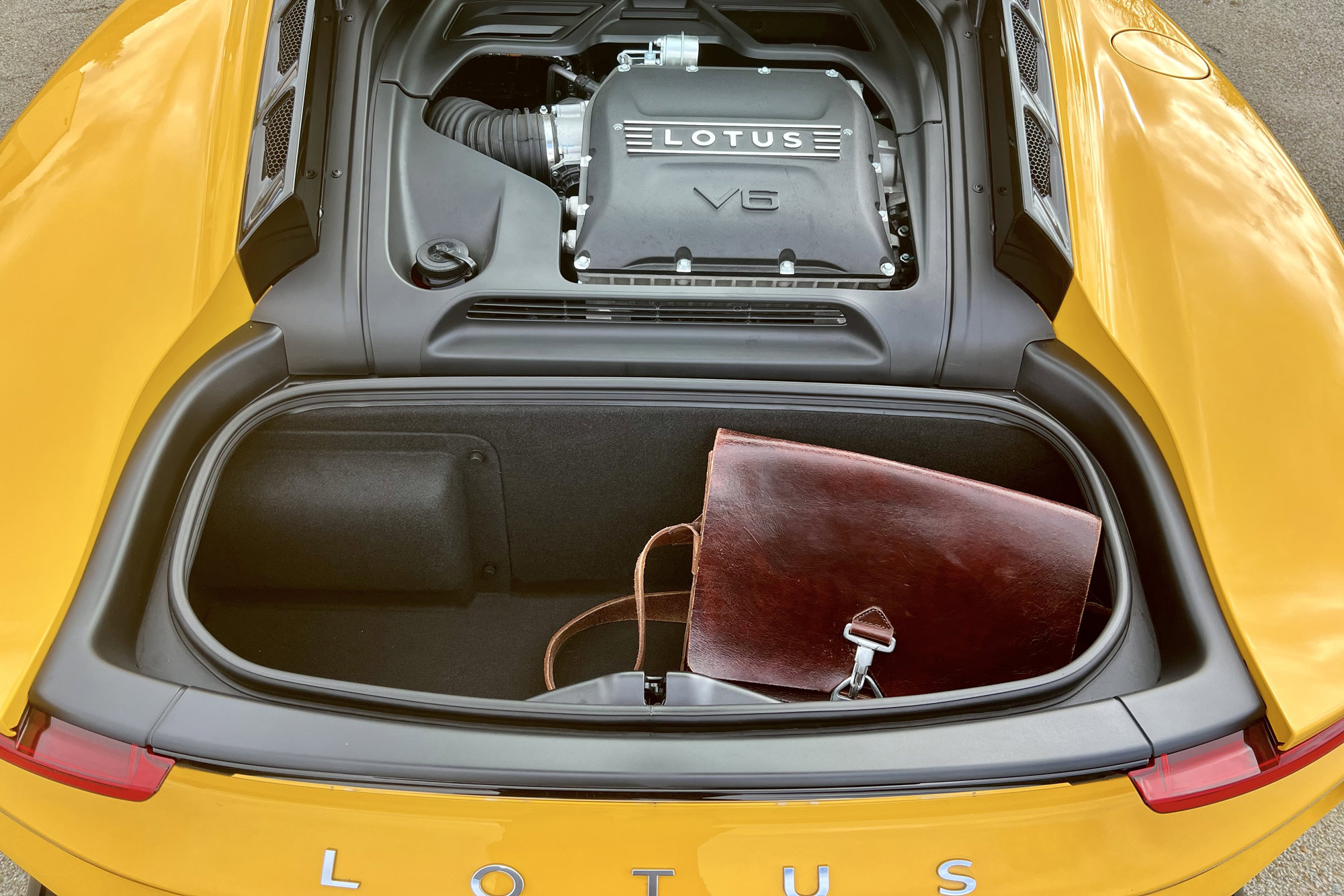 Yellow 2024 Lotus Emira cargo space with bag and V6 engine