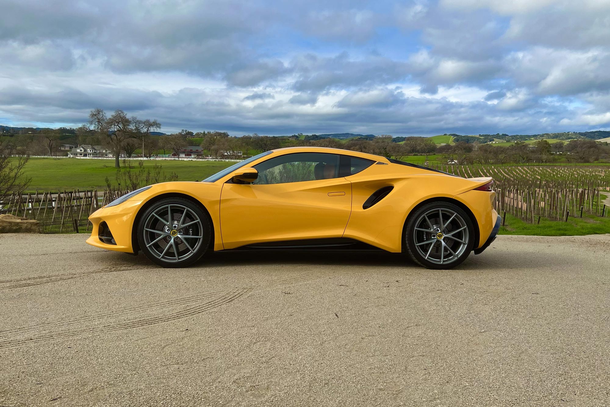 Yellow 2024 Lotus Emira side view parked by the fields