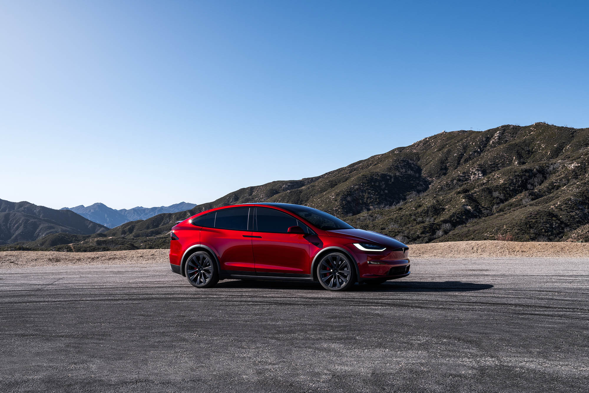 Red Tesla Model X parked in a mountainous area.
