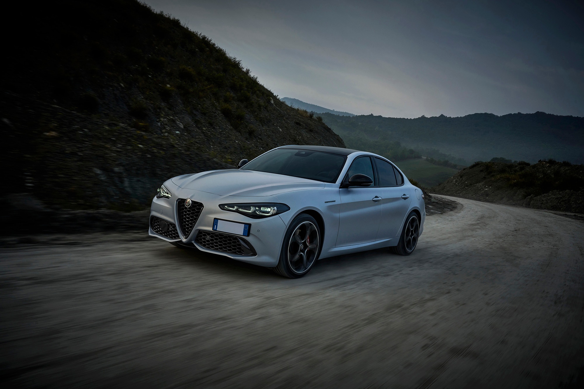 Alfa Romeo Giulia in silver matte paint driving up mountain road