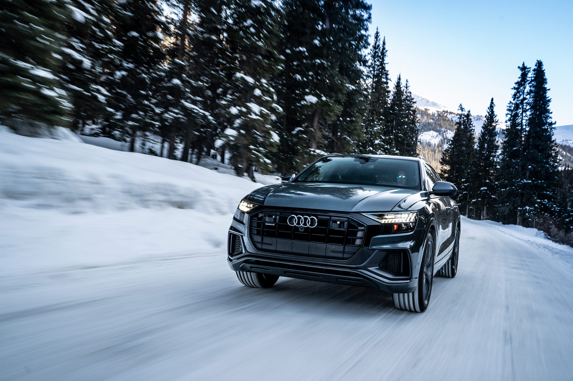 2022 Audi Q8 driving on snow-covered road in a forest.