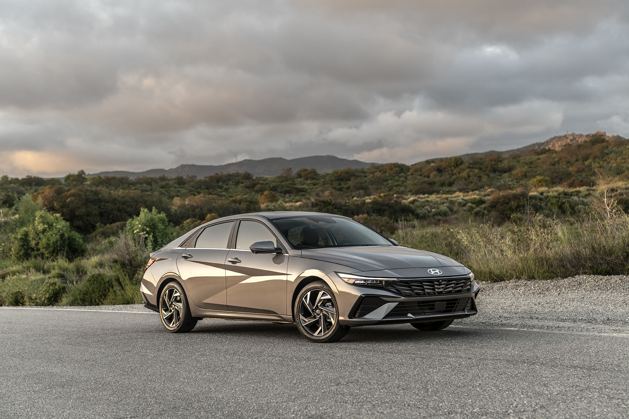 Gray Hyundai Elantra parked next to hills.