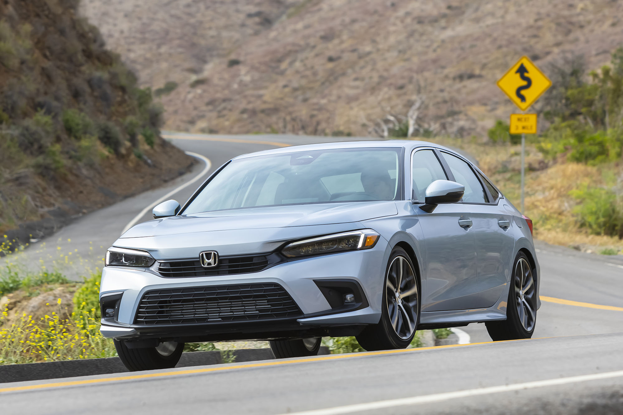 Silver Honda Civic driving down a twisty road.