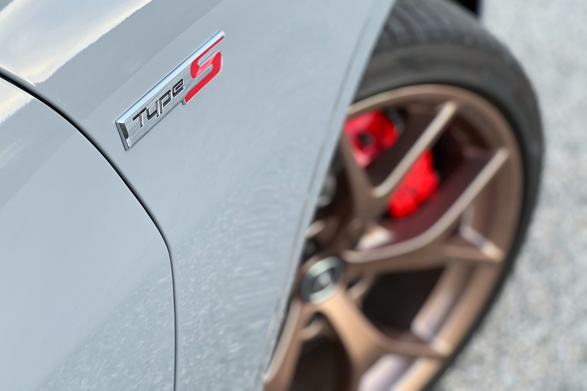 Close-up of a 2024 Acura TLX Type S fender badge in Urban Gray with copper-finish 20-inch wheels and red brake calipers