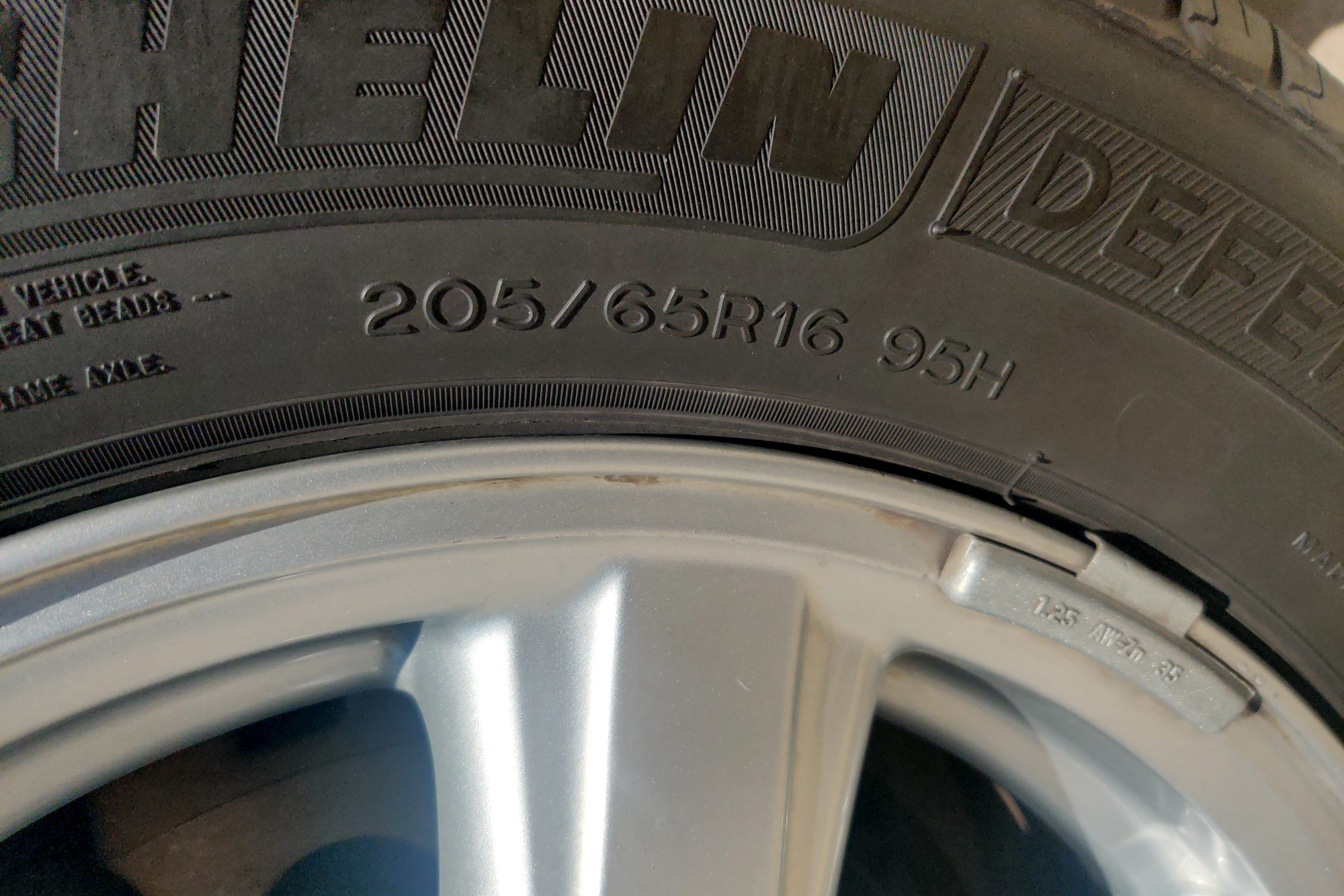 Close up view of tire sidewall showing size, load index, and speed rating.