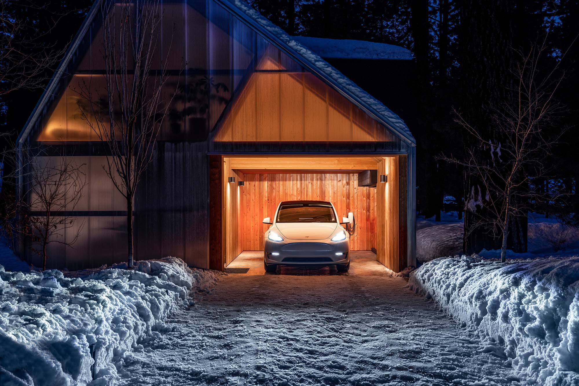 Tesla Model Y parked in garage with headlights on