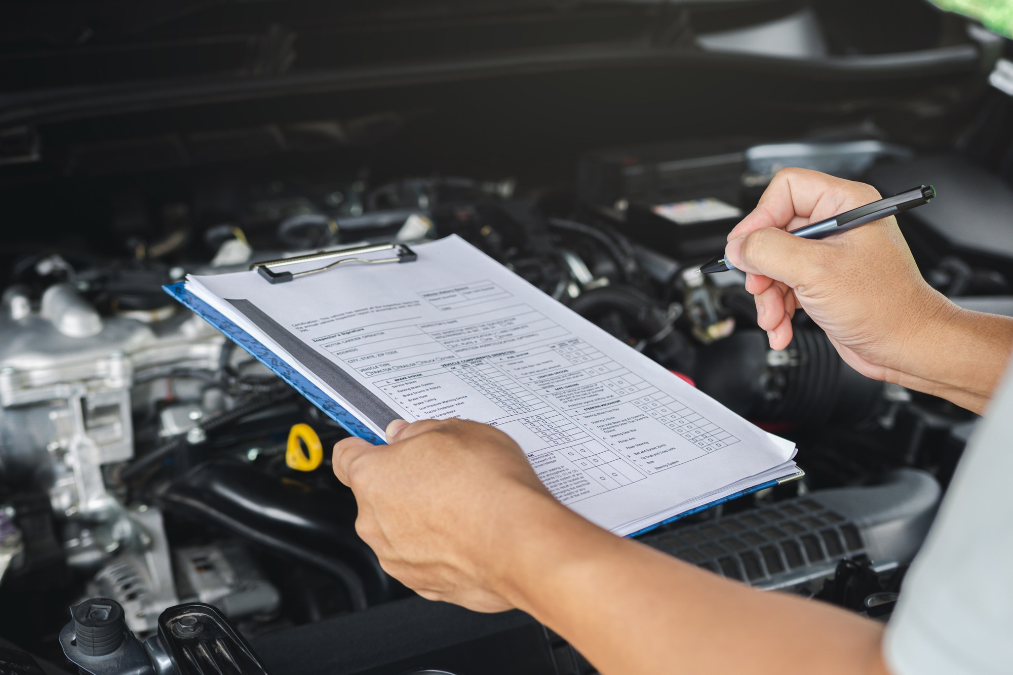 Man going over an inspection checklist overlooking an engine bay