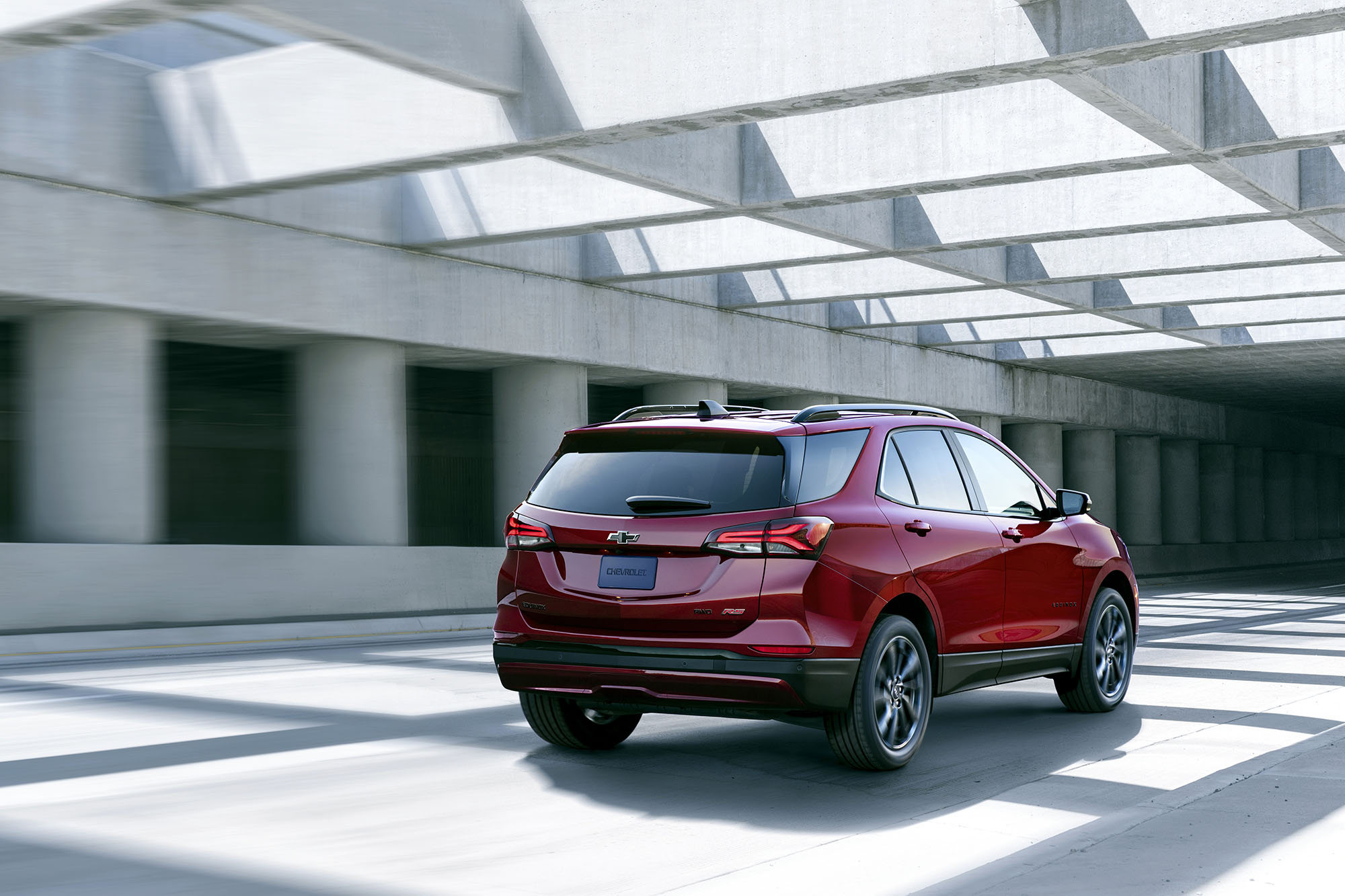 Red Chevrolet Equinox driving by concrete pillars.