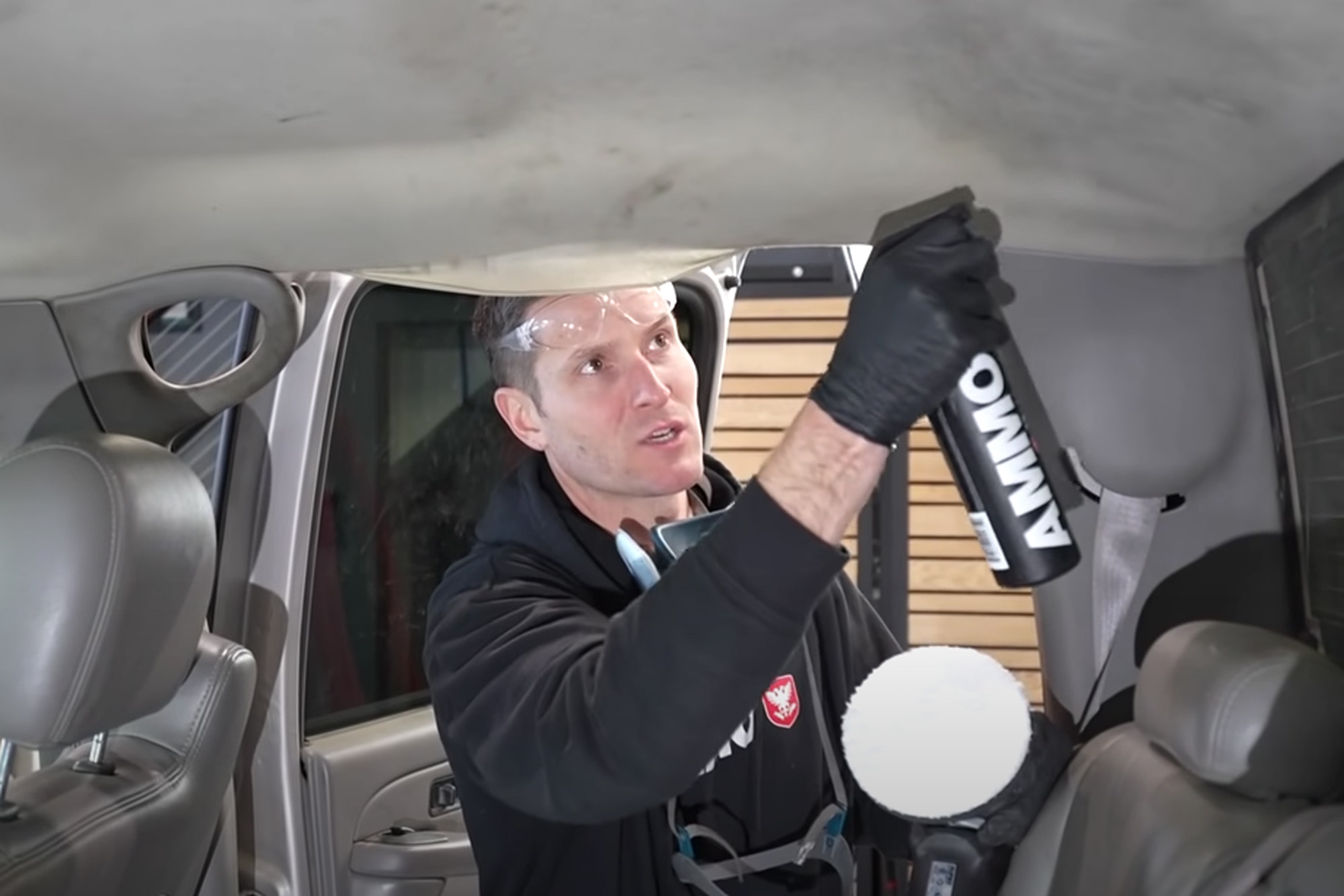 An auto detailer uses specialized spray cleaner on a car's headliner