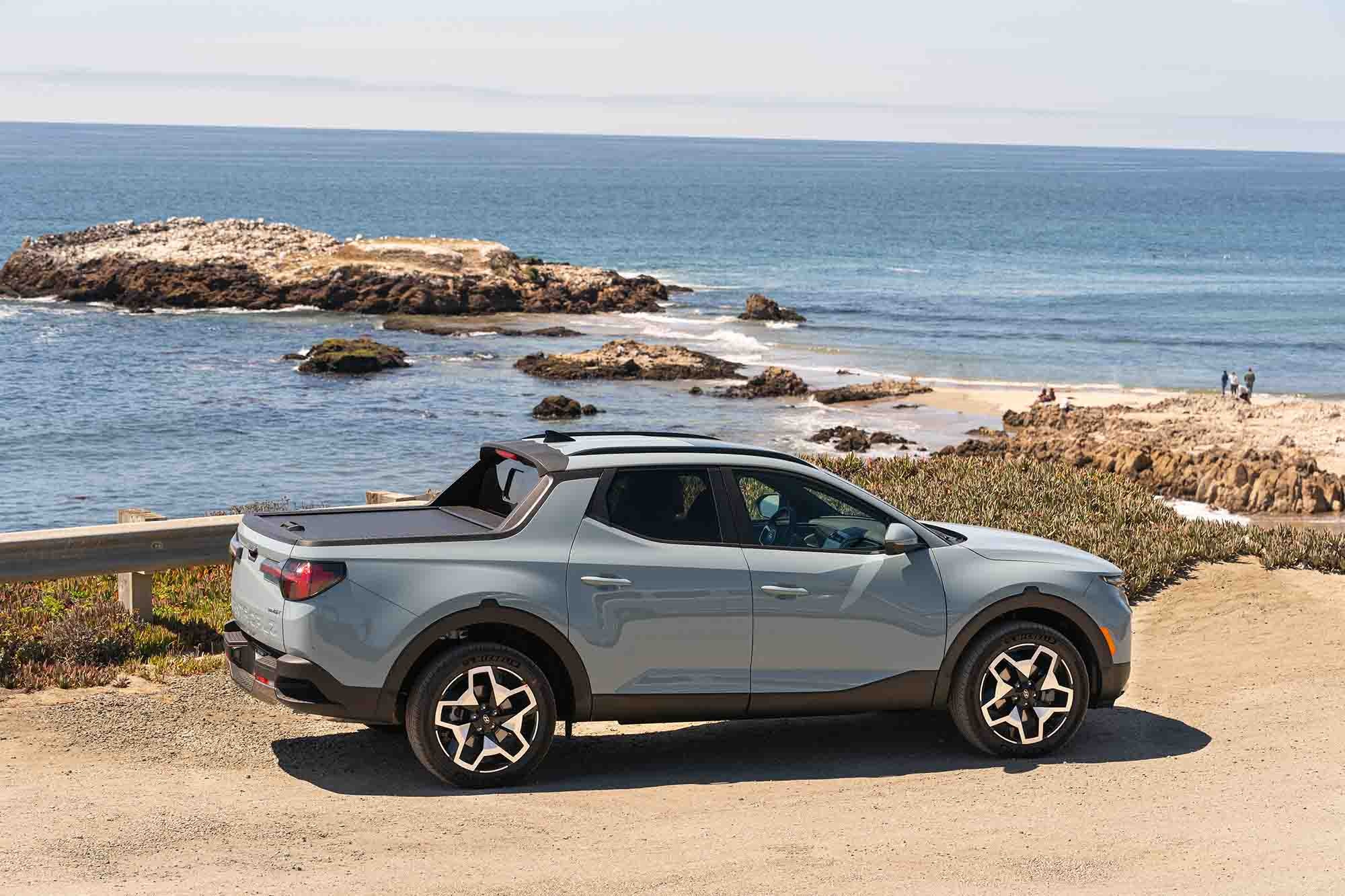  Light gray-blue Hyundai Santa Cruz parked near a beach with water in the background.