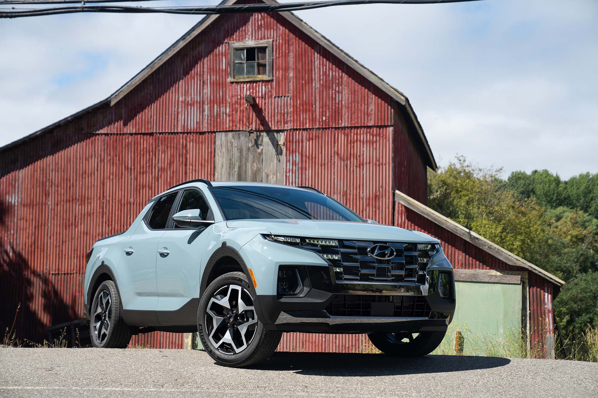  Blue-gray Hyundai Santa Cruz parked in front of a red barn.