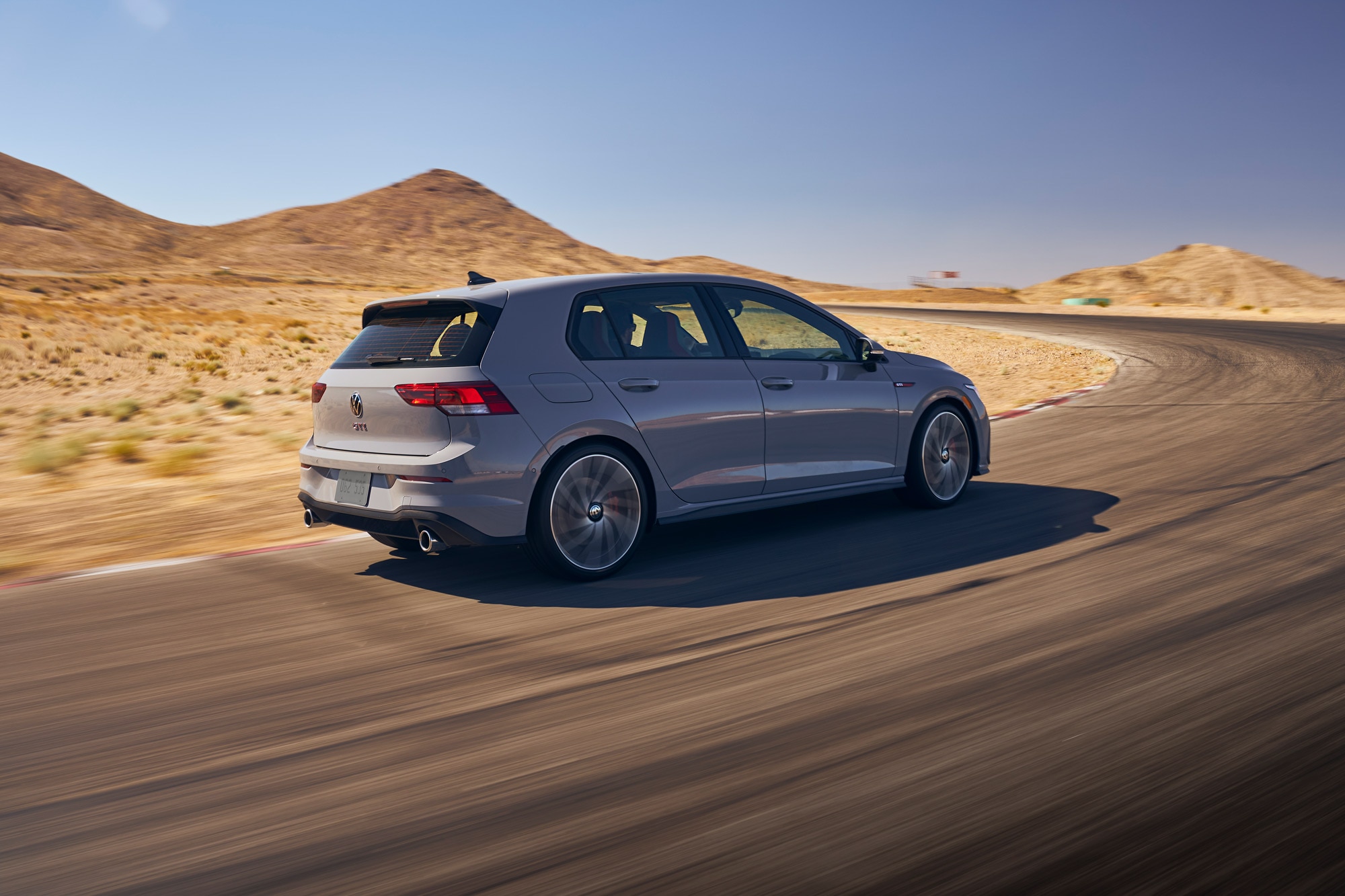 Volkswagen GTI driving on a racetrack in a desert.