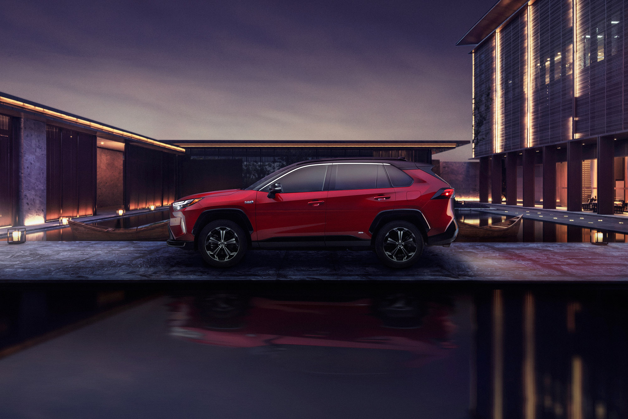 Red 2024 Toyota RAV4 Prime parked in an industrial area by a pool of water.