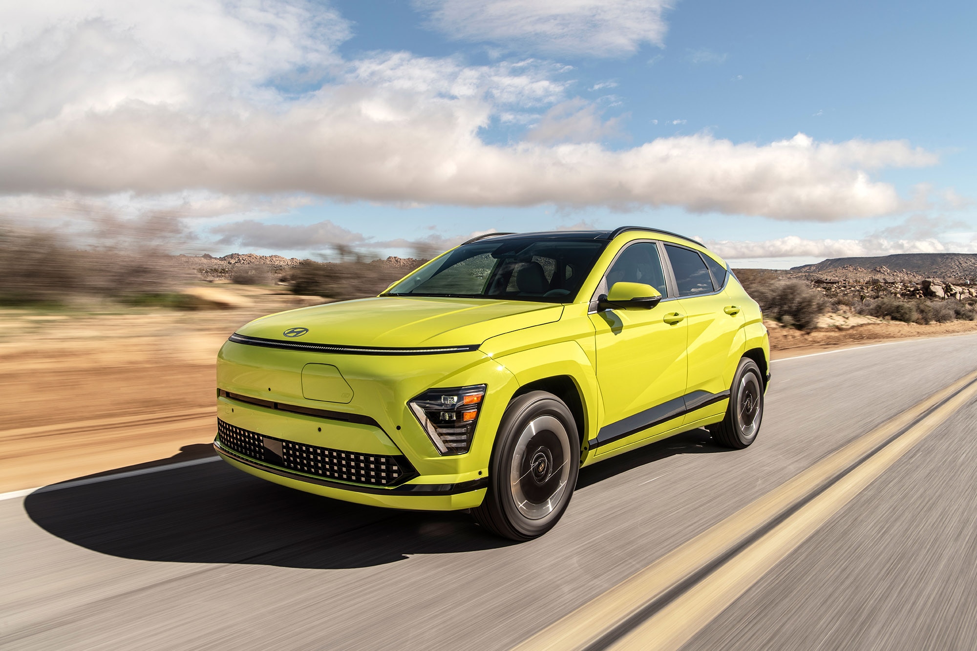 Yellow-green Hyundai Kona EV driving on paved road.