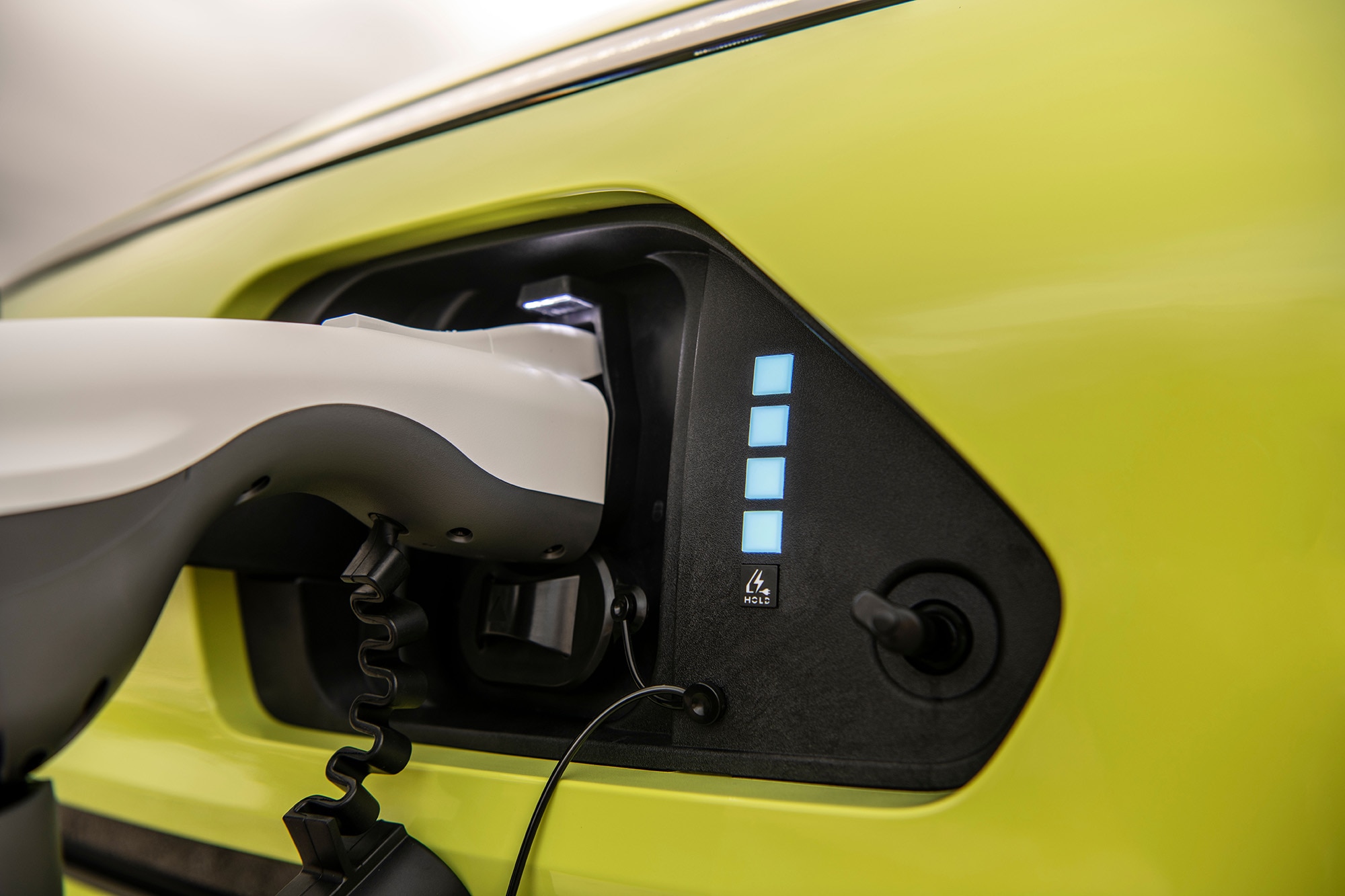 Yellow-green Hyundai Kona EV plugged into charger.