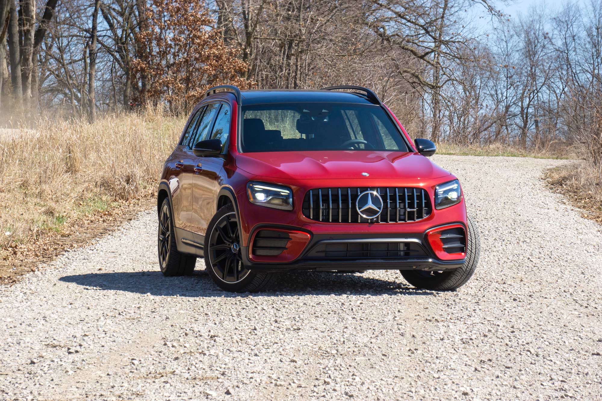 Front-quarter of a red 2024 Mercedes-AMG GLB 35 parked on a gravel road in the woods