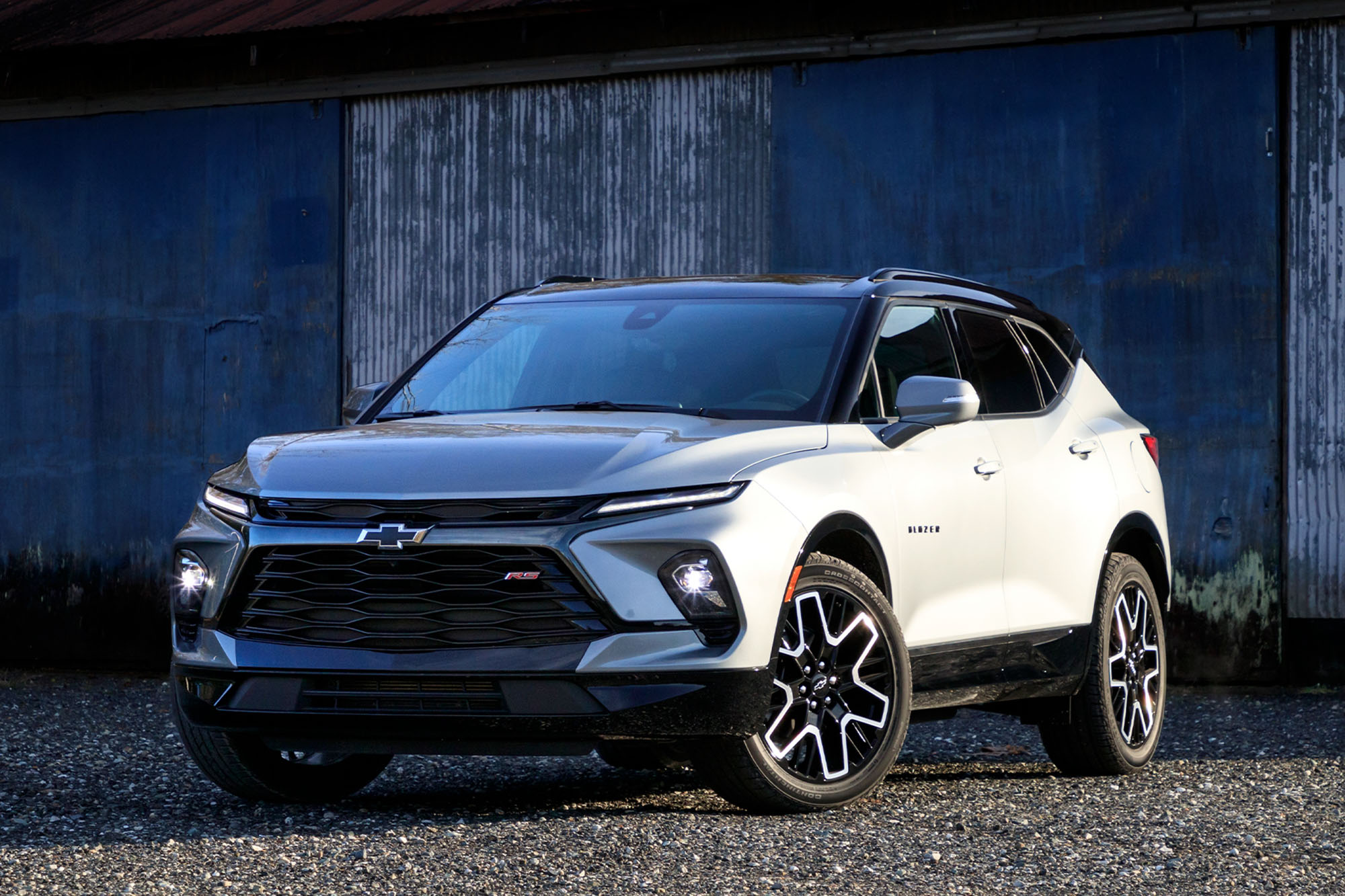 Front quarter view of a silver 2024 Chevrolet Blazer RS parked on gravel with a barn in the background.