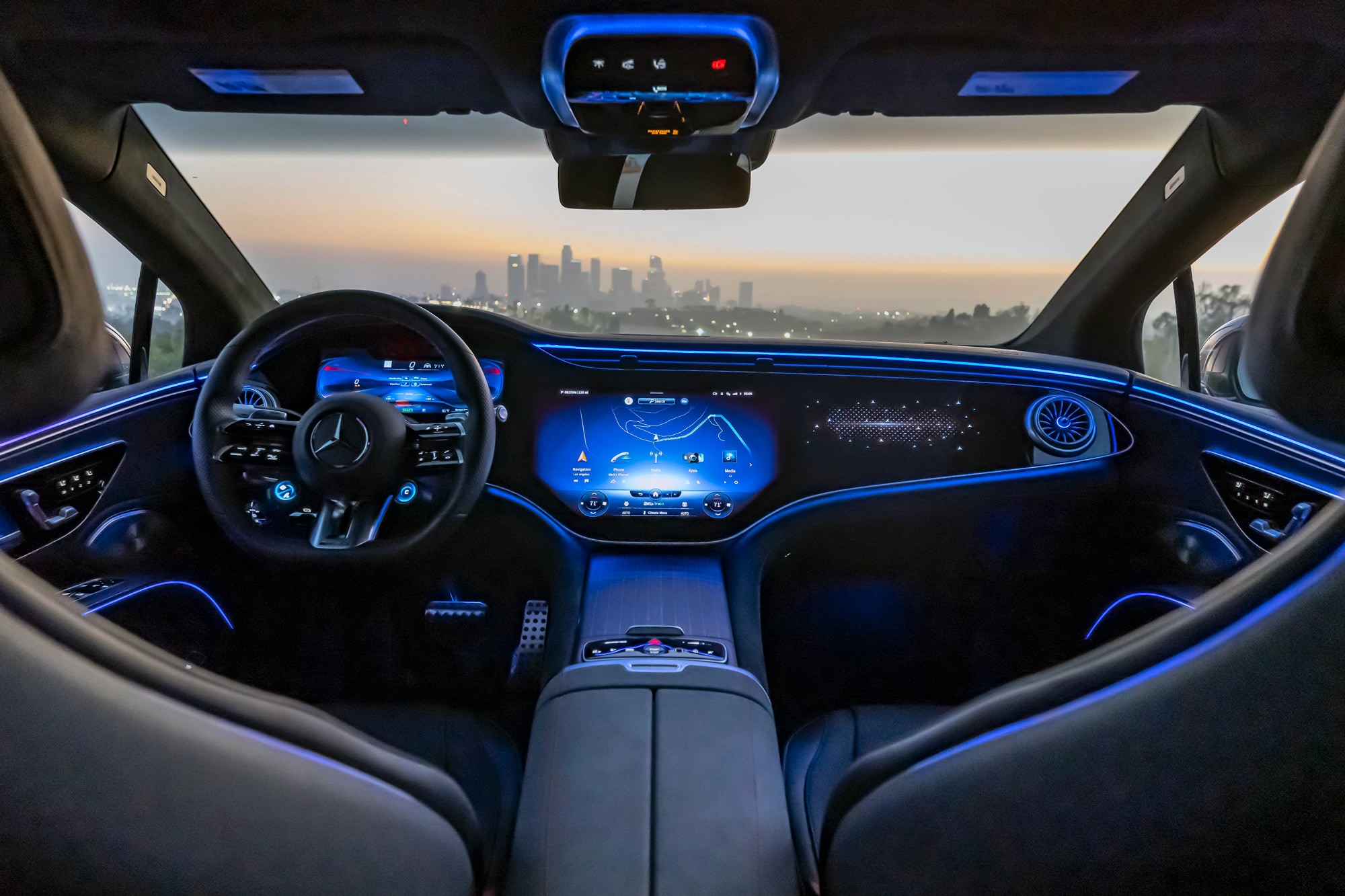 2022 Mercedes-AMG EQS infotainment screen, dashboard and front seats with city view at sunset