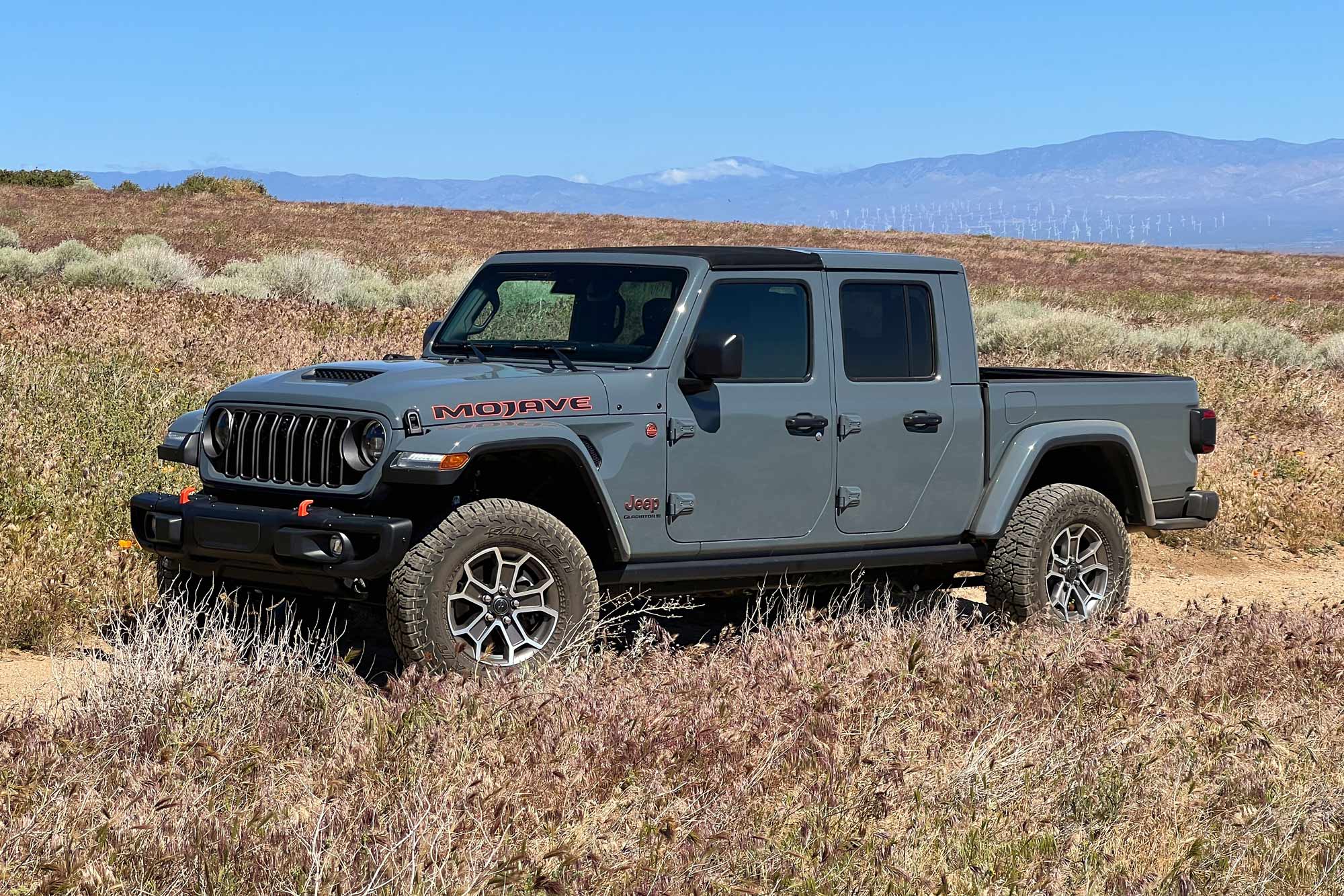 Front-quarter of a 2024 Jeep Gladiator Mojave X with Anvil paint parked on a high desert trail