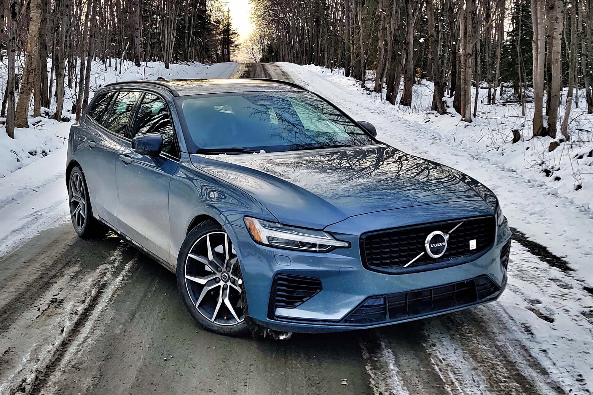 Front quarter view of a 2024 Volvo V60 Recharge Polestar Engineered parked on a snowy forest road lined by trees.