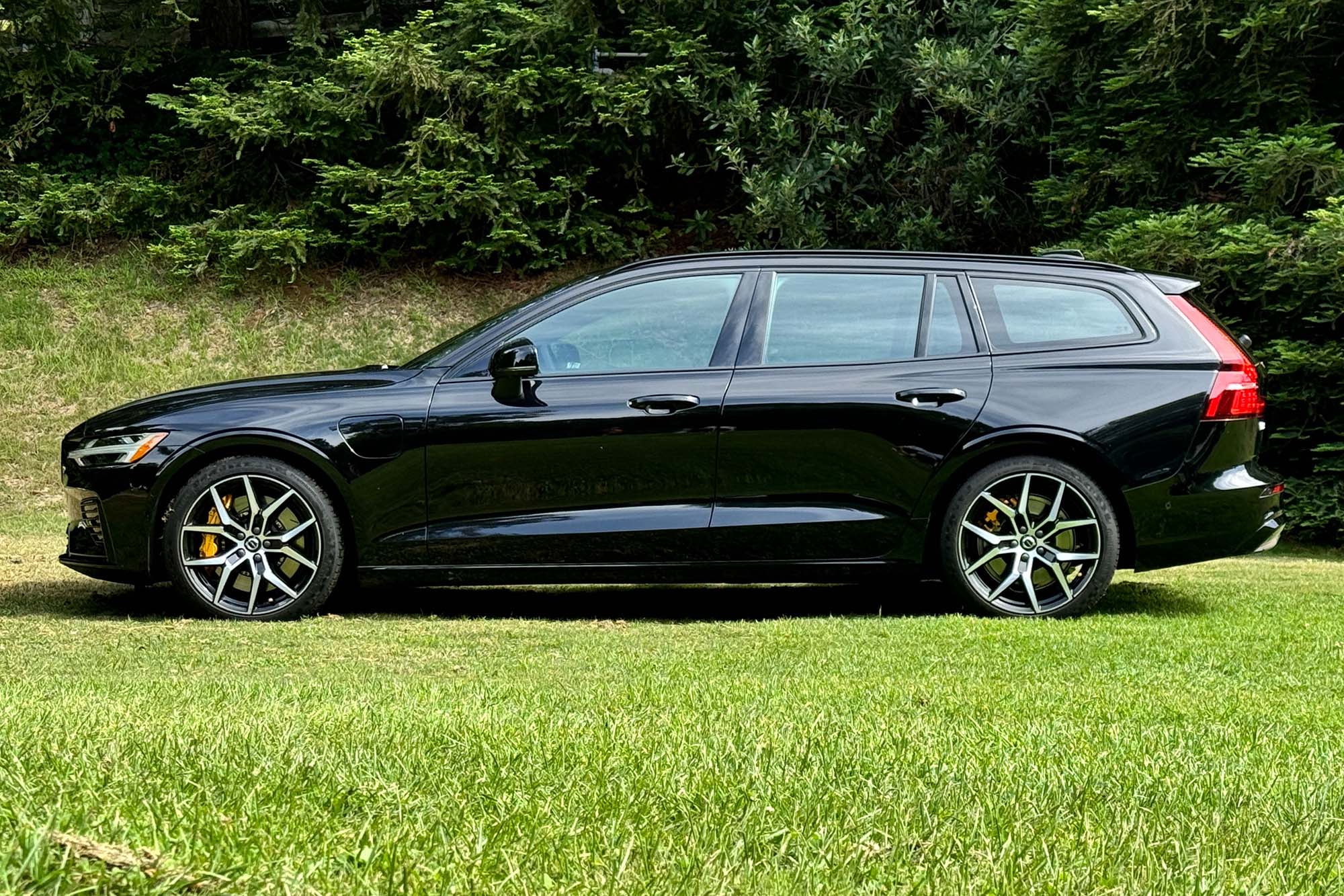 Side view of a black 2024 Volvo V60 Recharge Polestar Engineered parked on grass.