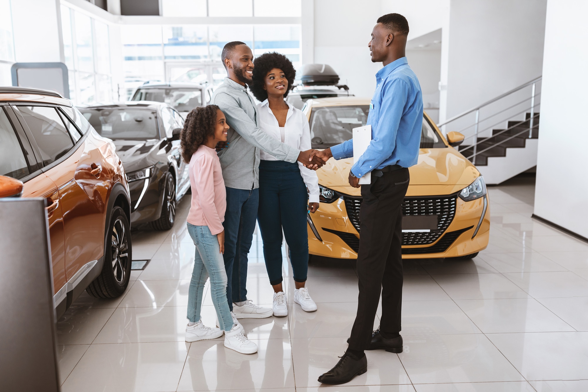 A couple and a child speak with a car salesperson