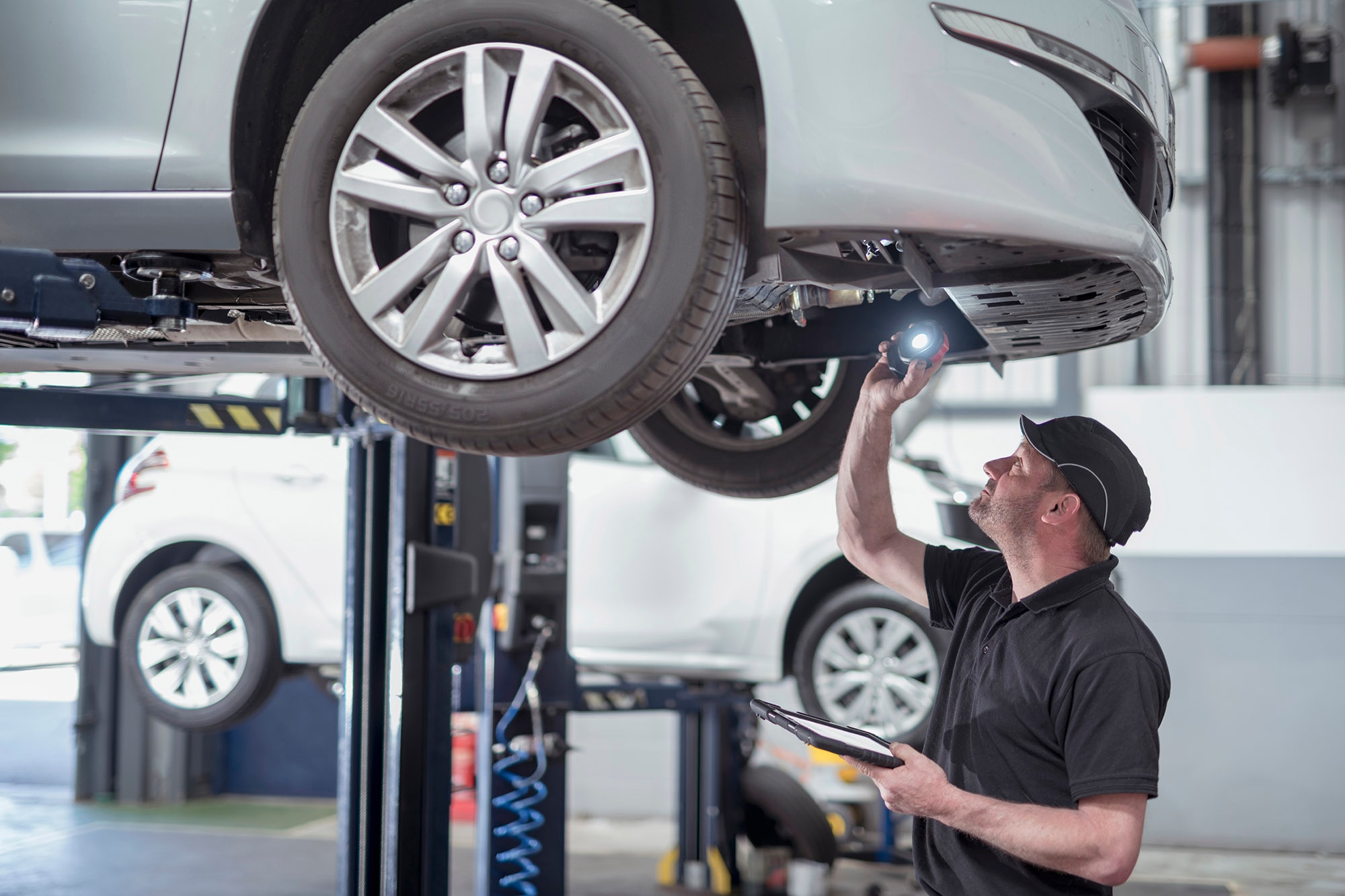 An auto technician inspects a vehicle on a lift 