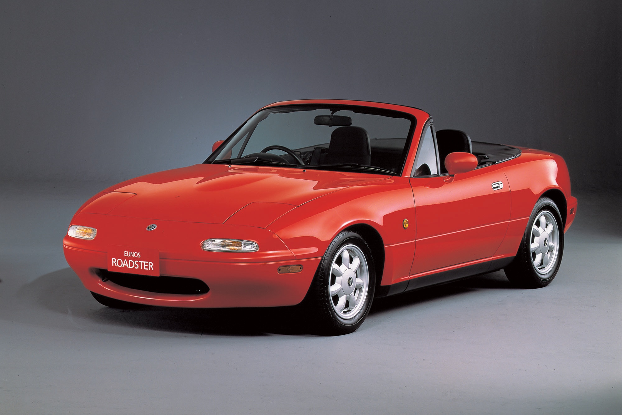 A red 1990 Mazda Miata with Japanese Domestic Market Eunos Roadster labeling