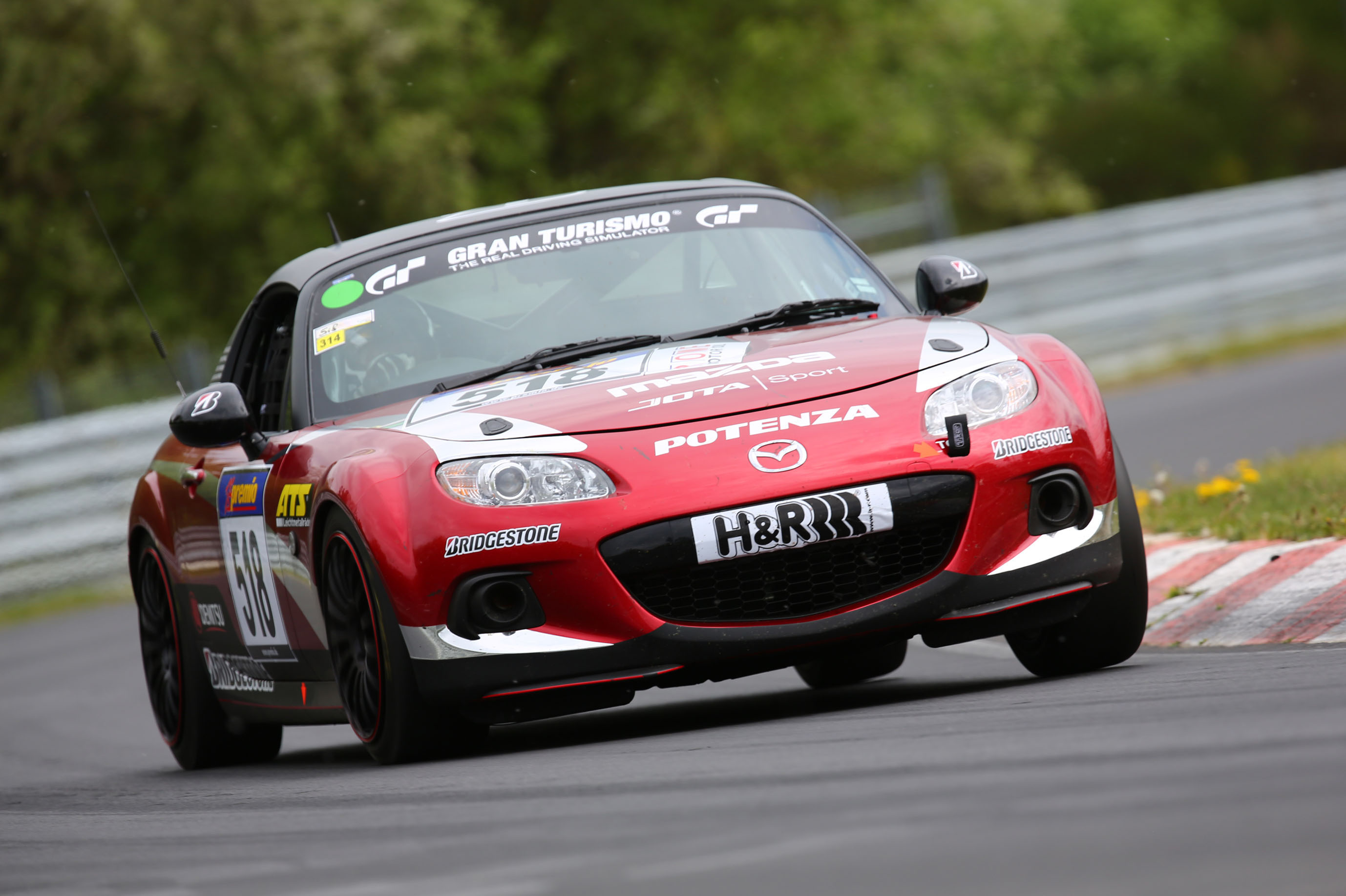 A red 2014 Mazda Miata racing at the N&uuml;rburgring in Germany