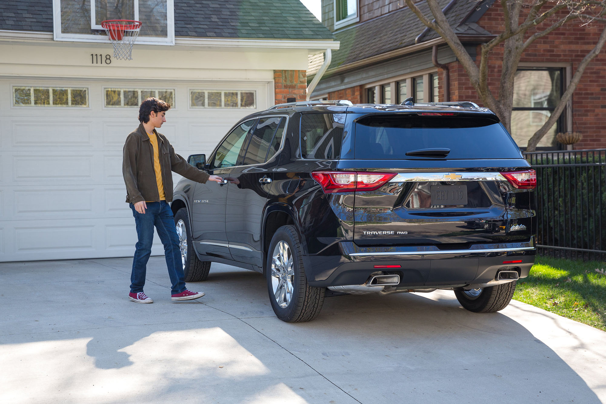 A teenager opening the door of a black Chevrolet Traverse.