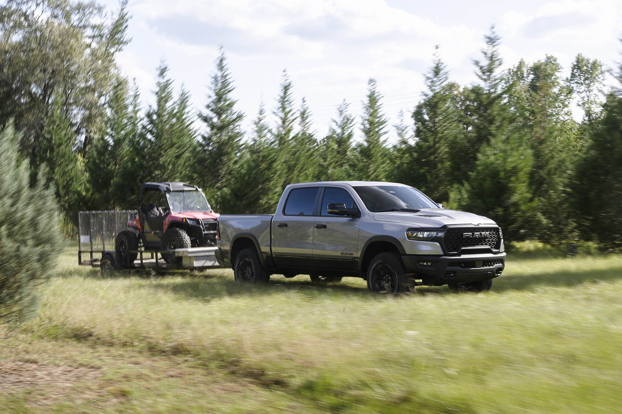 Ram 1500 towing a smaller vehicle on open trailer through grass.