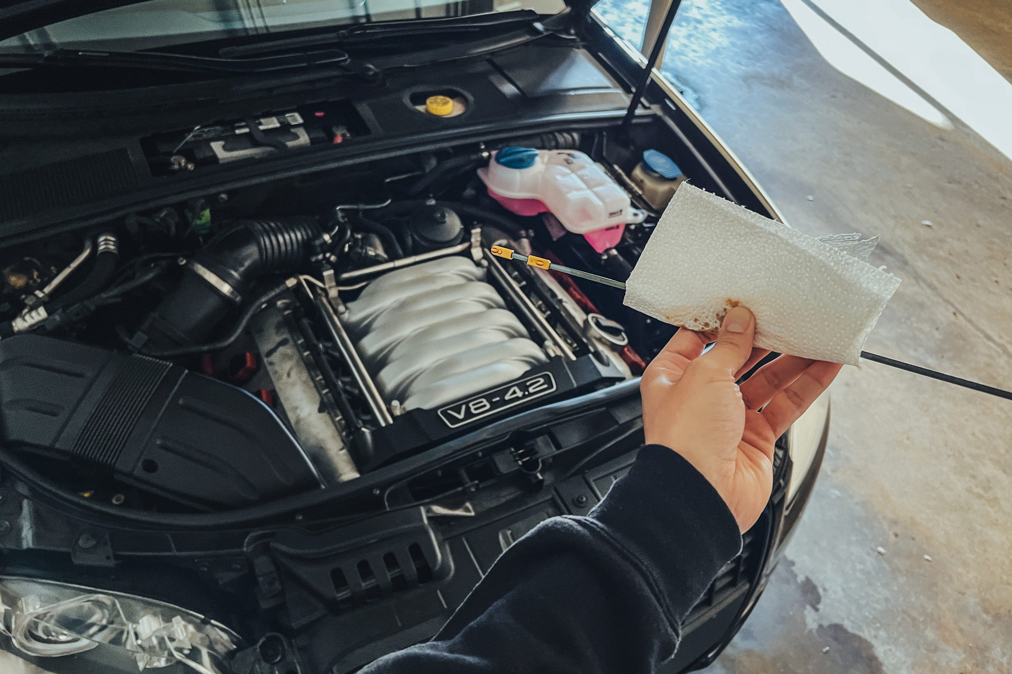 Person checking oil on dipstick of engine.