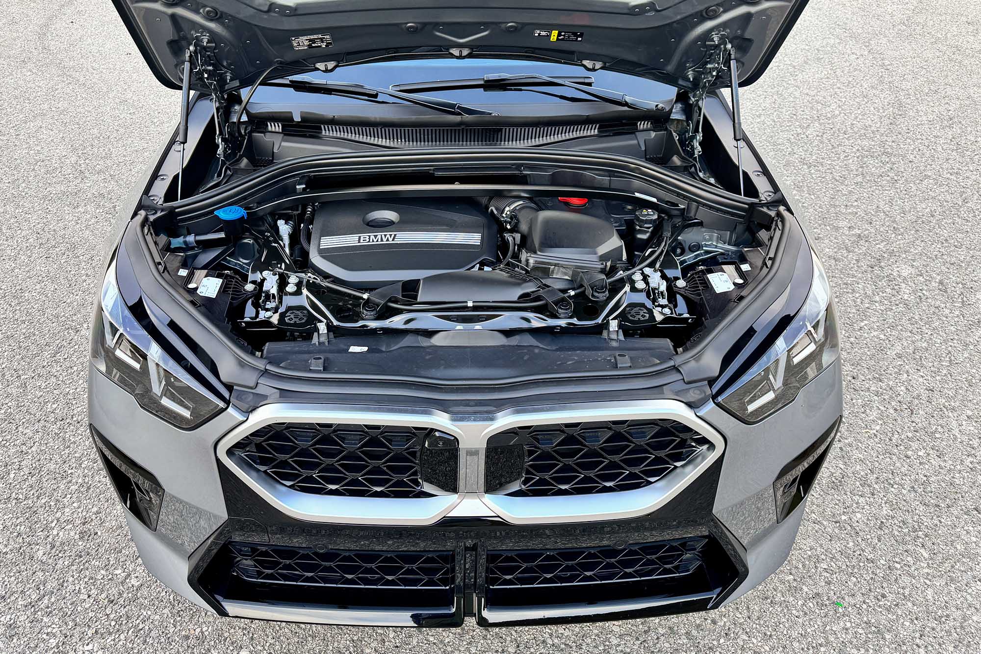 Gray 2024 BMW X2 with an open hood and the engine bay displayed.