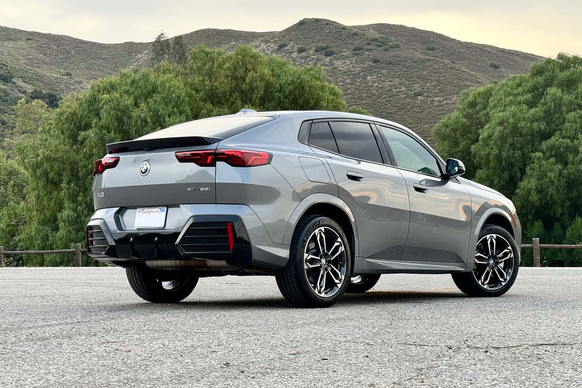 Gray 2024 BMW X2 parked on pavement with hills in the background.