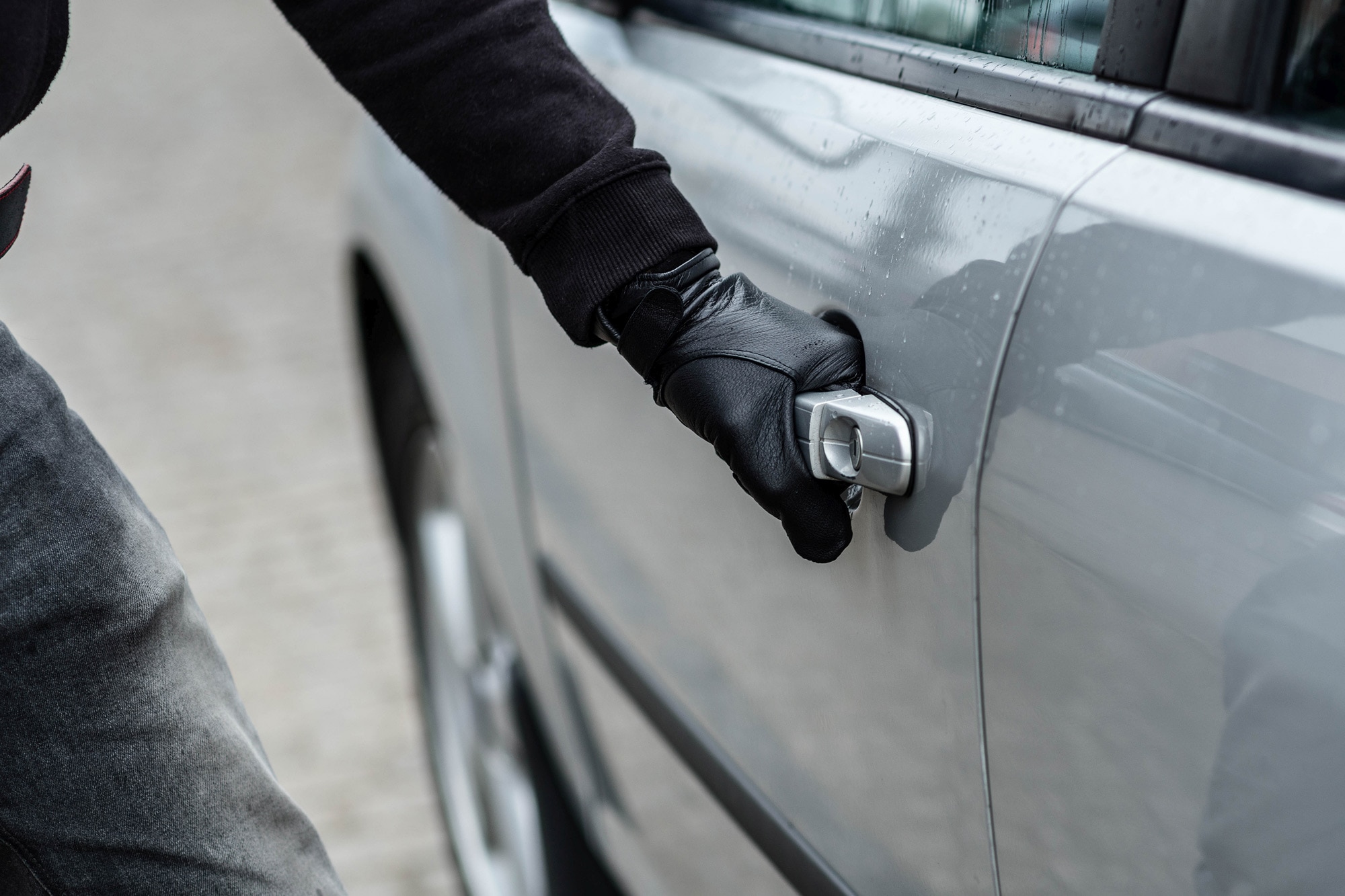 A person wearing gloves opens a car door