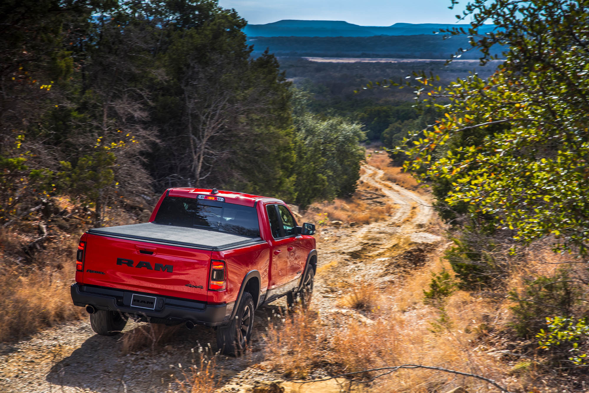 Red Ram 1500 truck driving down dirt track.