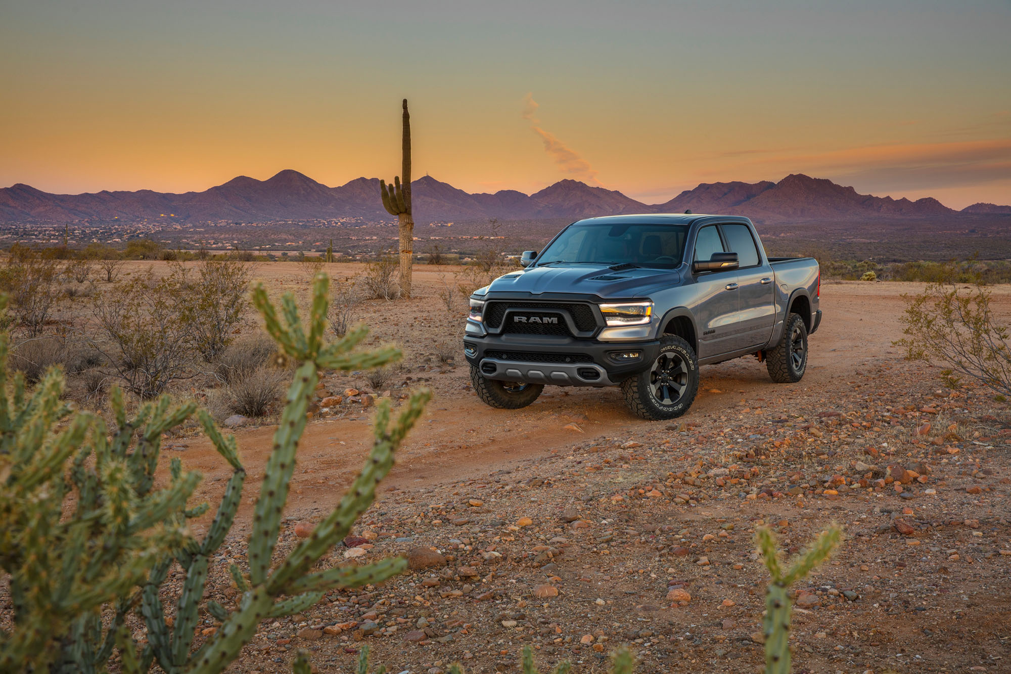 Silver Ram 1500 truck parked on a dirt road in the desert.