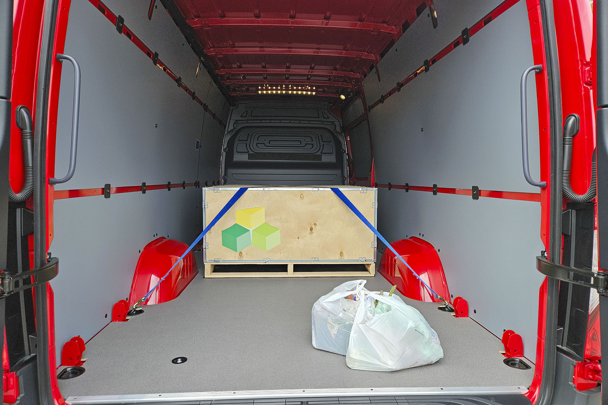 The cargo area of a 2024 Mercedes-Benz eSprinter, complete with a crate in the hold and grocery bags near the doors