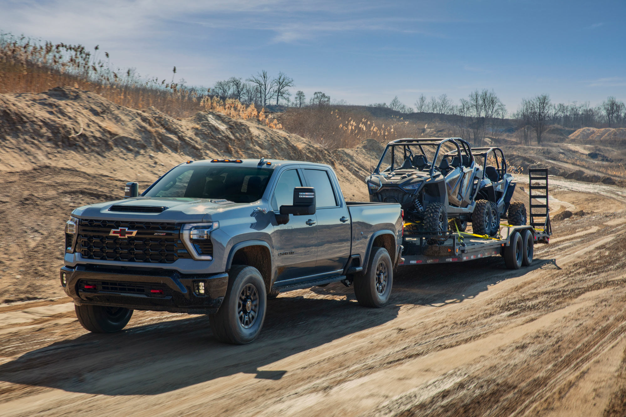 2024 Chevrolet Silverado HD towing two off-road vehicles on trailers.