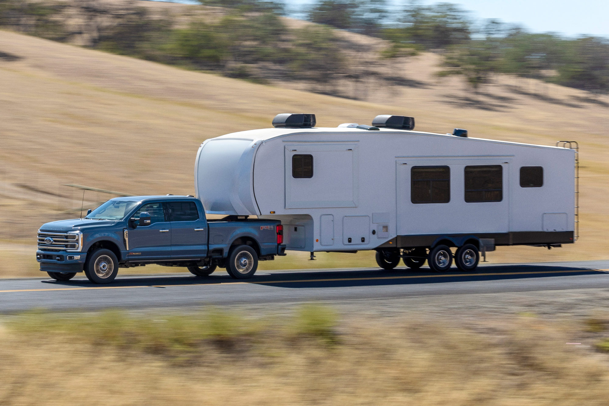 2023 Ford F-350 towing camper trailer on a highway.